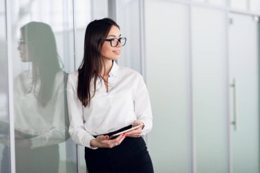 Young business woman with tablet computer opening glass office door