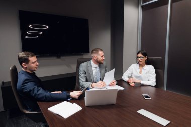 İş adamları toplantı odasında dizüstü bilgisayarlarıyla birlikte çalışıyorlar.