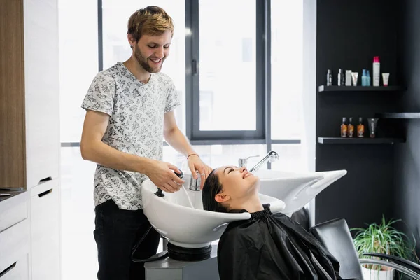 Žena dostává ošetření vlasů v lázeňském salonu pomocí šamponu na vlasy, kosmetický salon, mytí vlasů — Stock fotografie