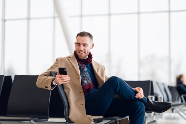 Porträt eines coolen Reisenden, der sich am Flughafen mit dem Handy entspannt — Stockfoto