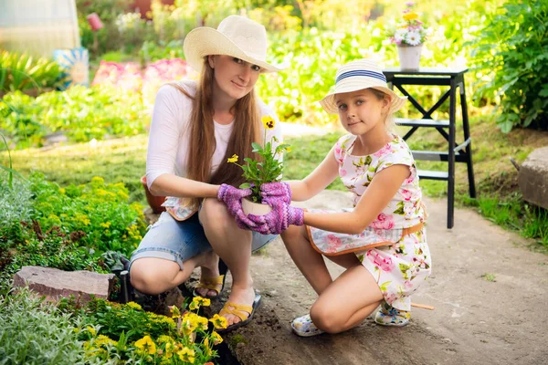Gardening, planting - mother with daughter planting flowers into the flowerpot — Stock Photo, Image