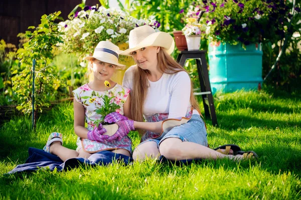 庭に花を植える女性と女の子、母と娘、園芸一緒に植えます。カメラを見ると — ストック写真