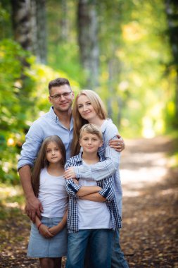 Mutlu aile dışarıda birlikte vakit geçiriyor. Baba, anne, kız ve oğul yazın bir yaz parkında eğleniyorlar.