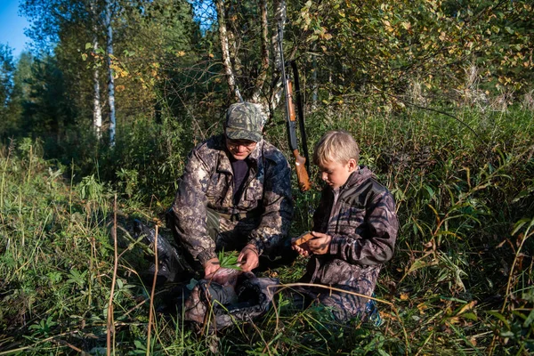 两个猎人的父亲和儿子在森林里一起吃饭。 丛林、狩猎和人的概念 — 图库照片