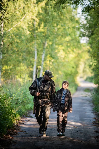 Apa és fia együtt vadásznak. Séta az úton az erdőben. — Stock Fotó