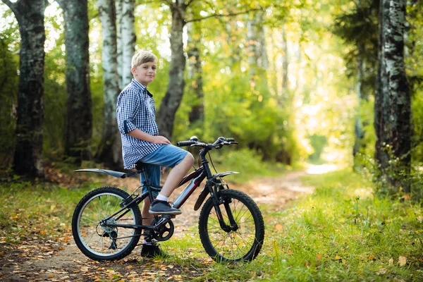 Teen boy rides a bicycle along a path in the forest. The cyclist rides fast through the springboards.