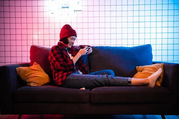 Nahaufnahme Porträt von hübschen Teenager-Mädchen beim Online-Spiel in Telefon trägt lässige Jeans Jeanshemd Outfit Kleidung sitzt auf einem gemütlichen Sofa — Stockfoto