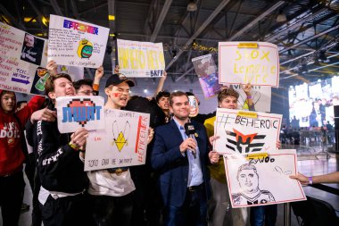 Moskova - 23 Aralık 2019: Profesyonel oyun etkinliği. Mikrofonlu bir haberci, en sevdikleri takımları destekleyen ve ellerinde büyük posterler tutan oyun fanatikleriyle röportaj yapıyor.