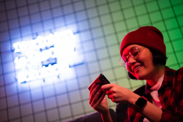 Teenager-Mädchen aufregend Smartphone spielen in einem Raum mit Neonfarbe zu Hause beleuchtet. — Stockfoto