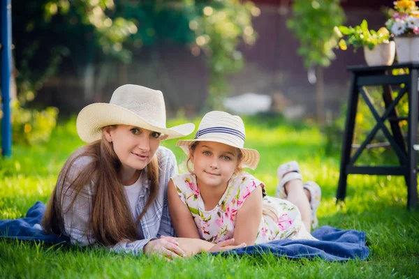 Maman et petite fille allongées sur l'herbe lors d'un pique-nique - Amour en l'air, une femme avec une fille sur le dos dans un moment d'intimité . — Photo