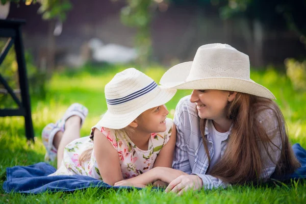 Maman et petite fille allongées sur l'herbe lors d'un pique-nique - Amour en l'air, une femme avec une fille sur le dos dans un moment d'intimité . — Photo