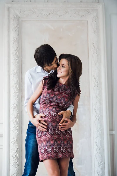 Krásný pár, těhotná mladá žena a muž objímání s láskou doma — Stock fotografie