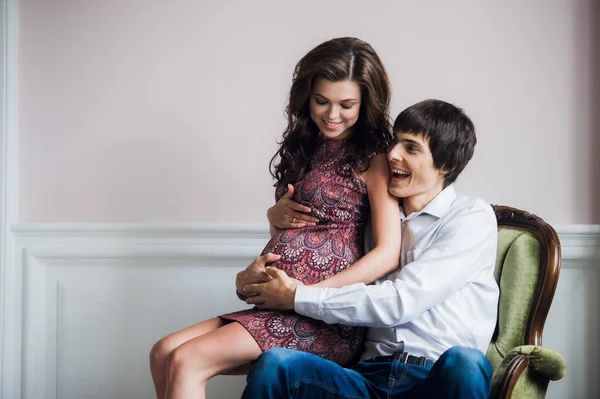 Sorridente coppia felice in attesa di un bambino si appoggia l'uno all'altro a casa — Foto Stock