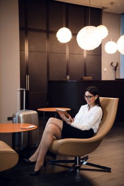 Havaalanındaki iş yerindeki tablette kulaklıkla müzik dinleyen bir kız..