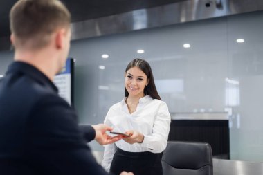 Havaalanında check-in masasında yolcudan pasaport alan güler yüzlü kadın personel