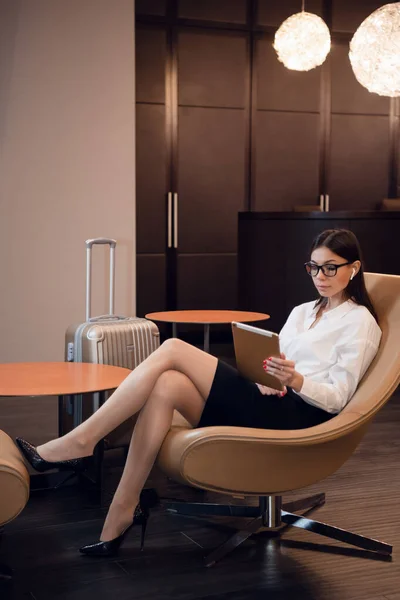 Chica escuchando música a través de auriculares en la tableta en el salón de negocios en el aeropuerto . —  Fotos de Stock