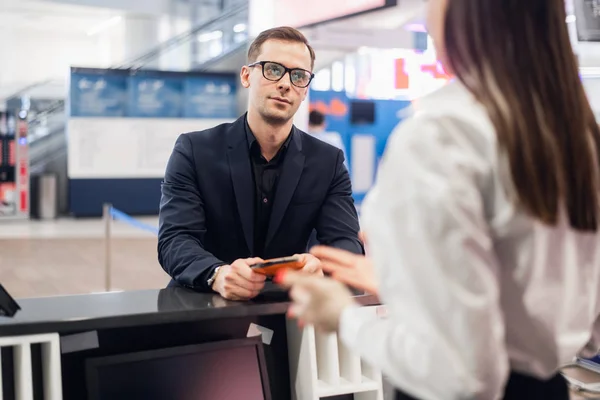 Przystojny biznesmen przekazujący bilet lotniczy przy kontroli linii lotniczych w kasie — Zdjęcie stockowe