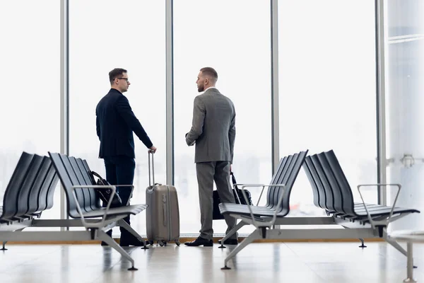 Compañeros de negocios esperando en el salón del aeropuerto de pie y hablando —  Fotos de Stock