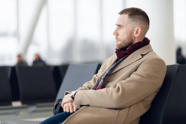 Zakenman zit op de luchthaven wachtkamer en wacht op de vlucht. Man executive in luchthaven business lounge zitten op wachtruimte. — Stockfoto