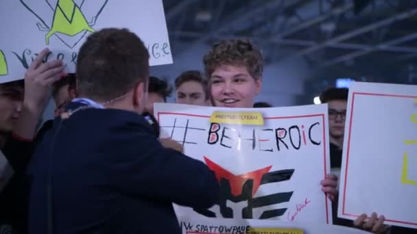 MOSCOW - DECEMBER 23 2019: esports professional gaming event. Newsman with microphone interviewing gaming fans which are cheering for favorite teams staying at fan zone and holding big posters — Stock Video