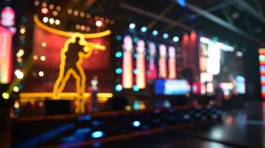 Blurred background of an esports event. Main stage, lights and flashes, illumination, big screens with game moments. Players compete on a stage.