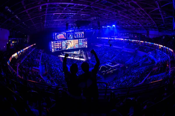 MOSCÚ, RUSIA - 14 DE SEPTIEMBRE DE 2019: evento de videojuegos de esports. Felices aficionados dedicados a los deportes electrónicos animando a su equipo favorito en una tribuna frente a una pantalla grande con la mano levantada . —  Fotos de Stock