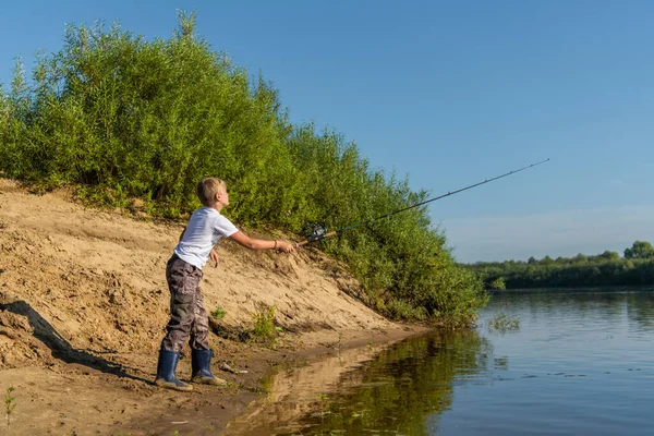 Foto eines kleinen Jungen, der an einem Sommertag im Freien fischt. — Stockfoto