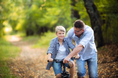 genç Baba gülümseyen oğlu nasıl bir bisiklet öğretim