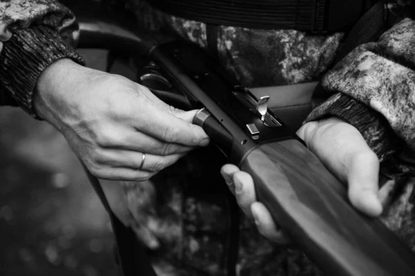 Hunter samec nabíjecí pistole, na sobě příležitostné lovecké oblečení, pažba a nůž na dolní části zad. Pozadí lesa. — Stock fotografie