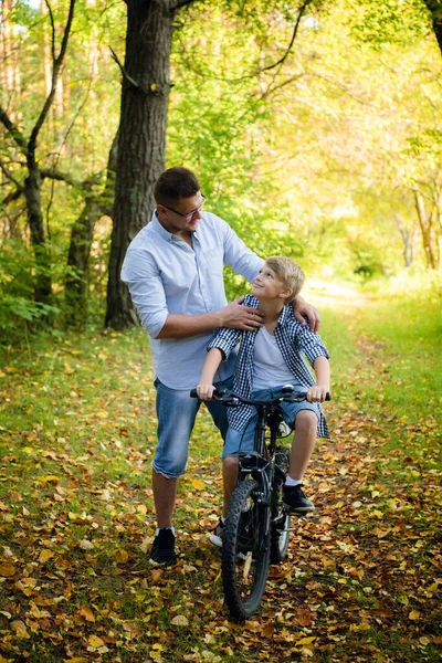 Jeune père enseignant à son fils souriant comment faire du vélo — Photo