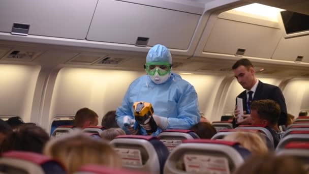 Moscou - 04 mars 2020. Contrôle de la température d'un virus corona dans l'avion. Un fonctionnaire médical portant une suite de protection contre les maladies infectieuses mesure la température des passagers à l'intérieur de l'aéronef à l'arrivée . — Video