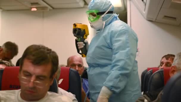 Moskova - Mart 04 2020. Uçaktaki korona virüsünün sıcaklığı kontrol edildi. Bulaşıcı hastalıkları koruma süiti giyen tıbbi görevli, uçağın içindeki yolcuların hava sıcaklığını ölçüyor.. — Stok video