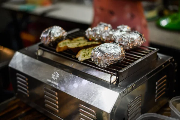 Patatas en papel de aluminio a la parrilla en la barbacoa, comida de verano —  Fotos de Stock