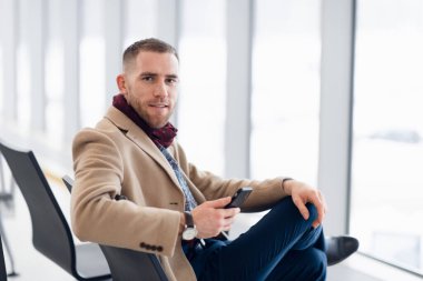 onun telefonu kullanırken kalkış Havaalanı'nda bekleyen genç meşgul adam