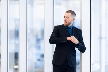 Cam kapının önünde takım elbiseli ve kravatlı yakışıklı bir adamın portresi.