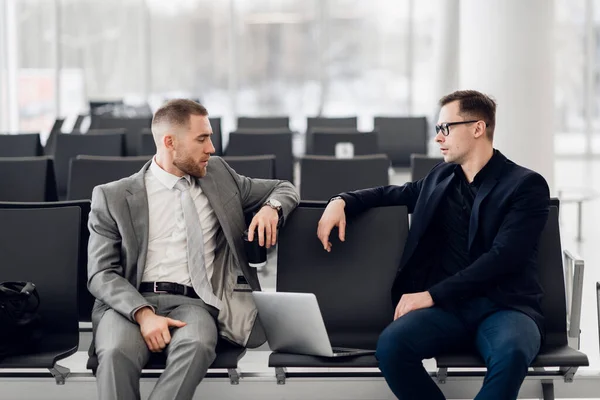 Compañeros de negocios esperando en el salón del aeropuerto de pie y hablando —  Fotos de Stock