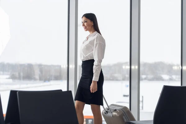 Retrato de una joven mujer de negocios vestida con ropa elegante caminando por el vestíbulo del hotel con su maleta —  Fotos de Stock