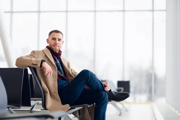 Молодий бізнесмен чекає в залі очікування в аеропорту і він перевіряє час на годиннику . — стокове фото
