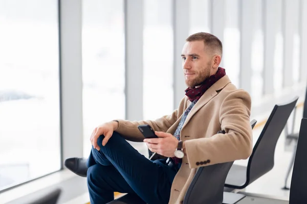 Porträt eines coolen Reisenden, der sich am Flughafen mit dem Handy entspannt — Stockfoto