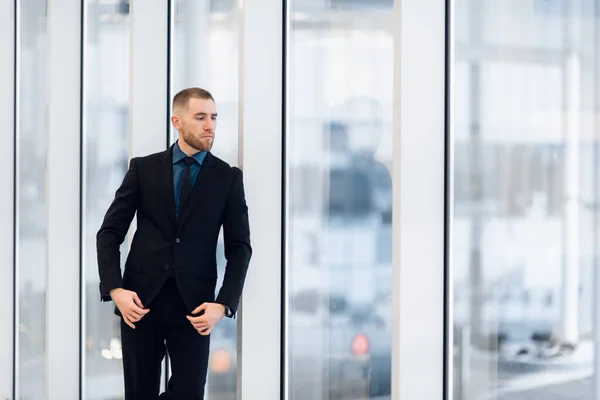Porträt eines gutaussehenden Mannes, der in Anzug und Krawatte vor einer Glastür steht — Stockfoto