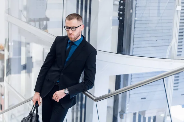 Hochwinkelaufnahme Foto von attraktiven reifen Mann in schicker Formalwear. Mit Telefon und Koffer in der Hand steigt er die Treppe hinauf. — Stockfoto
