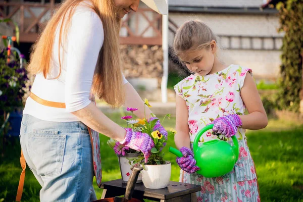 Woman gardener helping her daughter to pour garden flower pot. — Stock Photo, Image