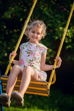Sevimli kız yaz günü salıncakta eğleniyor.