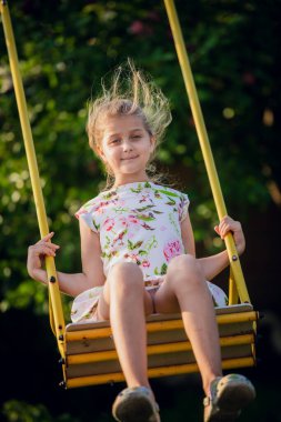 Sevimli kız yaz günü salıncakta eğleniyor.