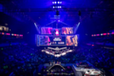 Esport etkinliğinin arka planında bulanıklık var. Büyük bir stadyumdaki bilgisayar oyunları turnuvasının büyük bir sahnesi aydınlandı. Tribünler video oyunu hayranlarıyla dolu..