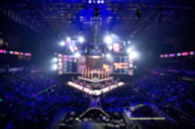 Esport etkinliğinin arka planında bulanıklık var. Büyük bir stadyumdaki bilgisayar oyunları turnuvasının büyük bir sahnesi aydınlandı. Tribünler video oyunu hayranlarıyla dolu..