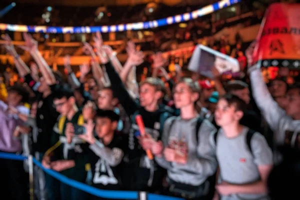 Blurred background of an esports event - A lot of fans on a tribune at tournaments arena with hands raised. Cheering for their favorite team. — Stock Photo, Image