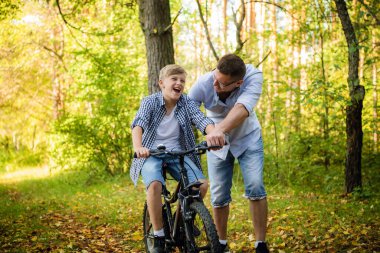 genç Baba gülümseyen oğlu nasıl bir bisiklet öğretim