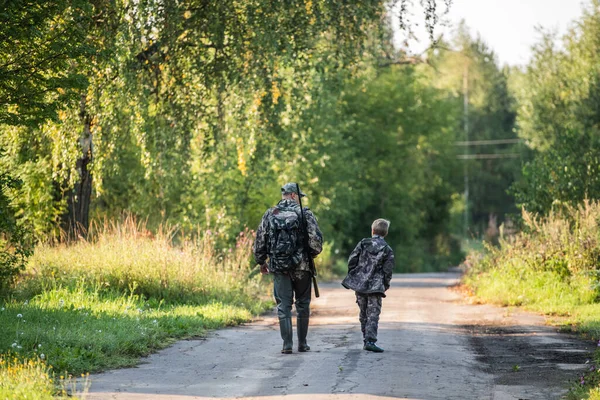 Père et fils chassent ensemble. Marcher sur la route dans une forêt . — Photo