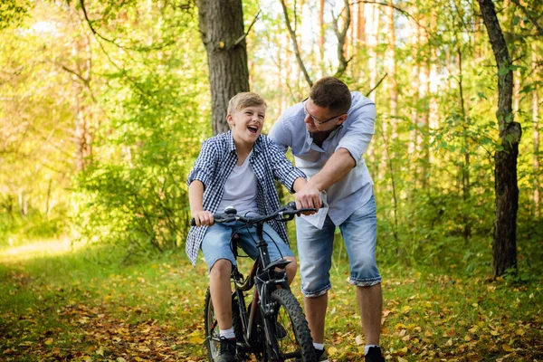 Jeune père enseignant à son fils souriant comment faire du vélo — Photo